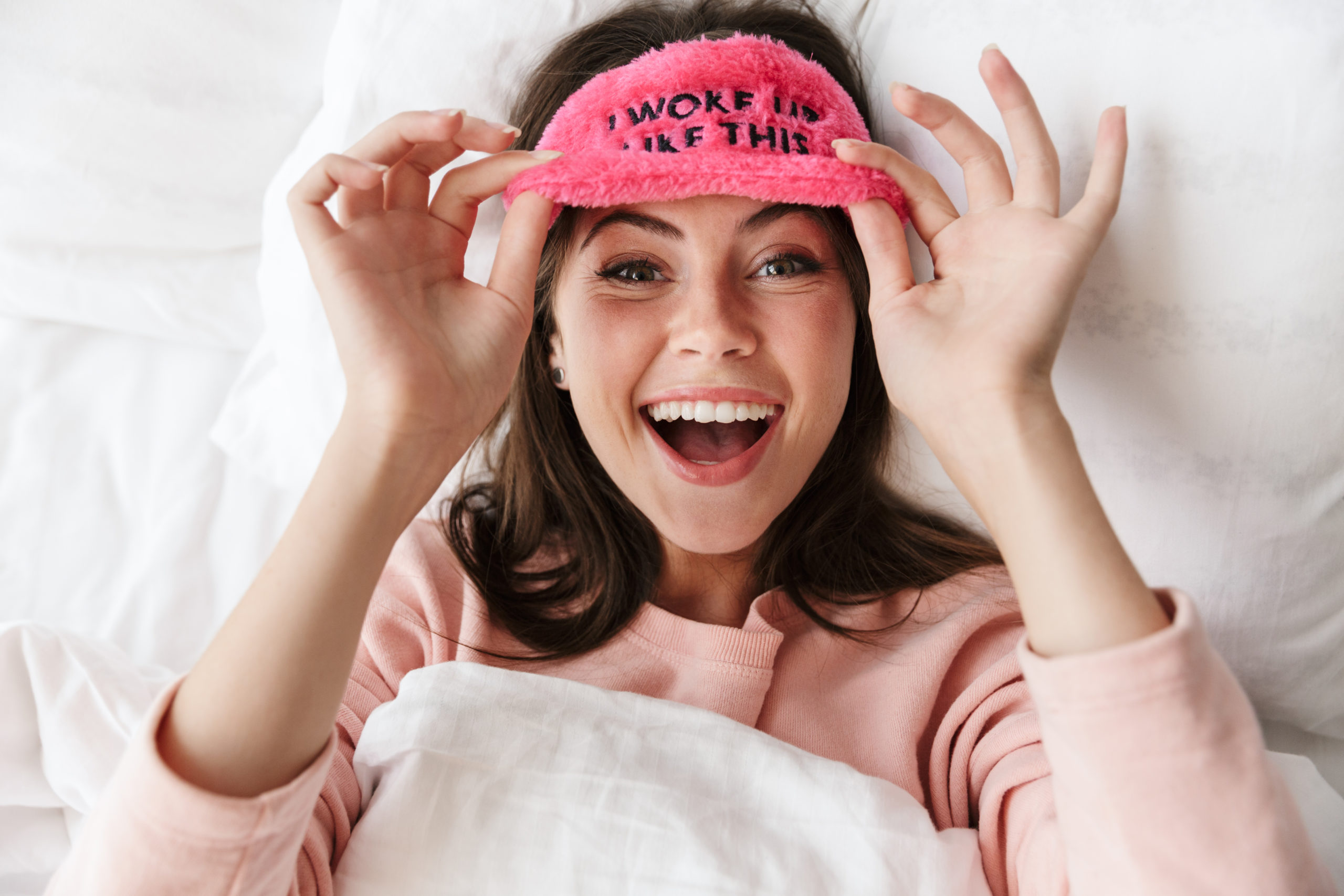 Cheerful lovely young girl wearing pajamas laying in bed