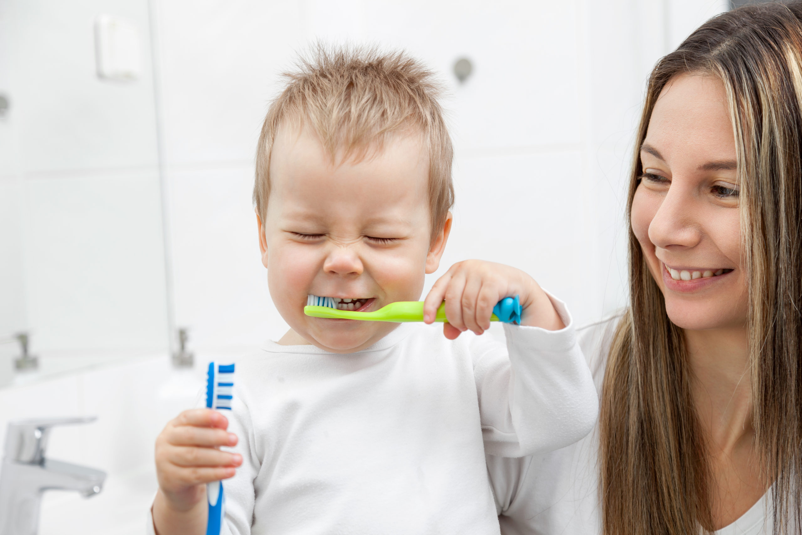 Happy mother teaching her son how to bush teeth