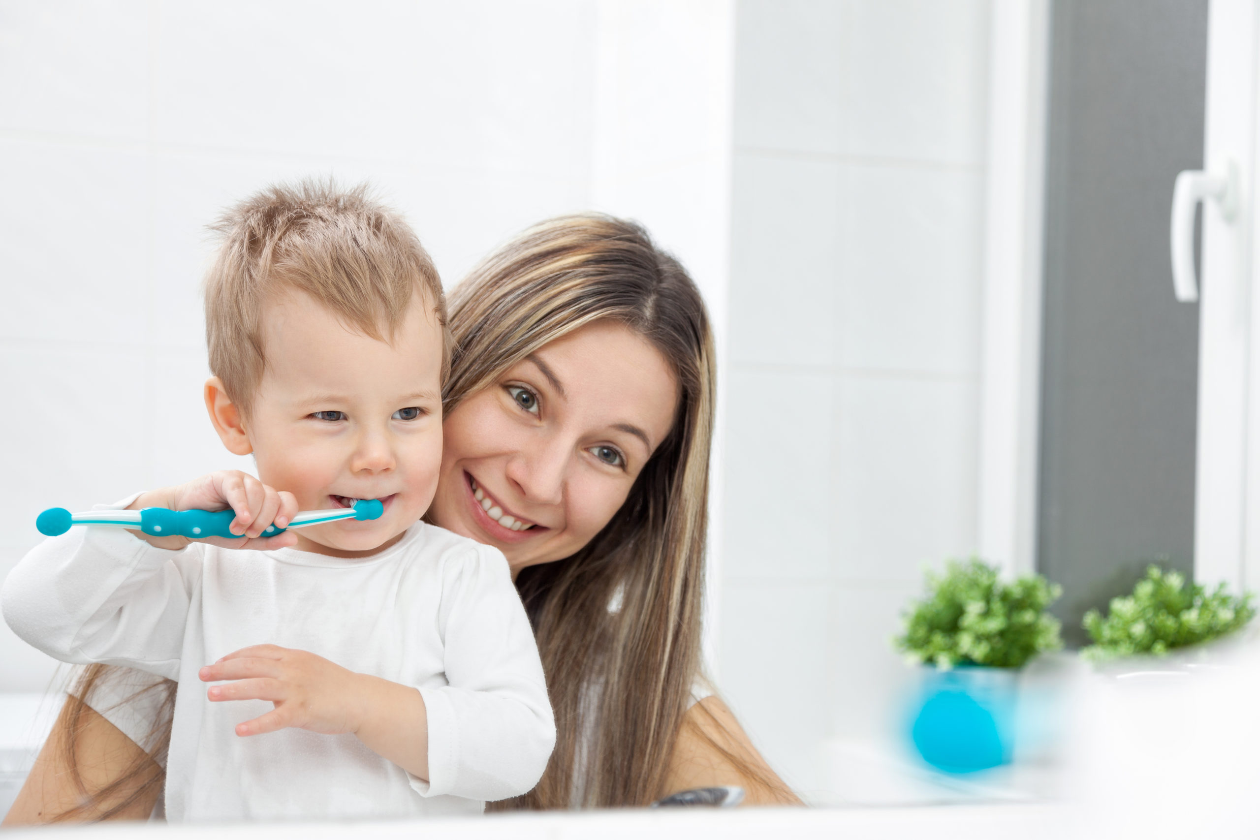 Happy mother teaching her son how to bush teeth