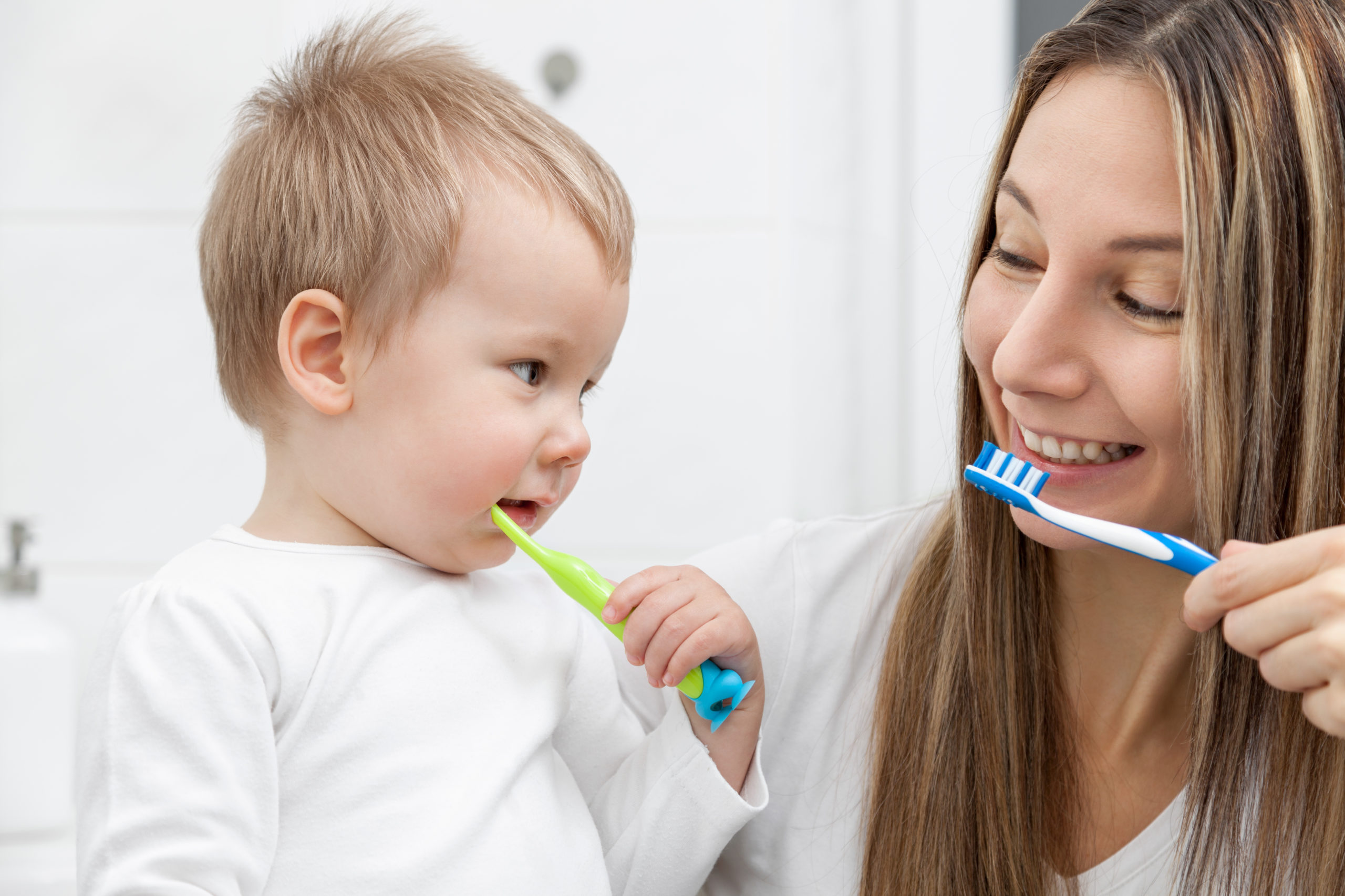 Happy mother teaching her son how to bush teeth